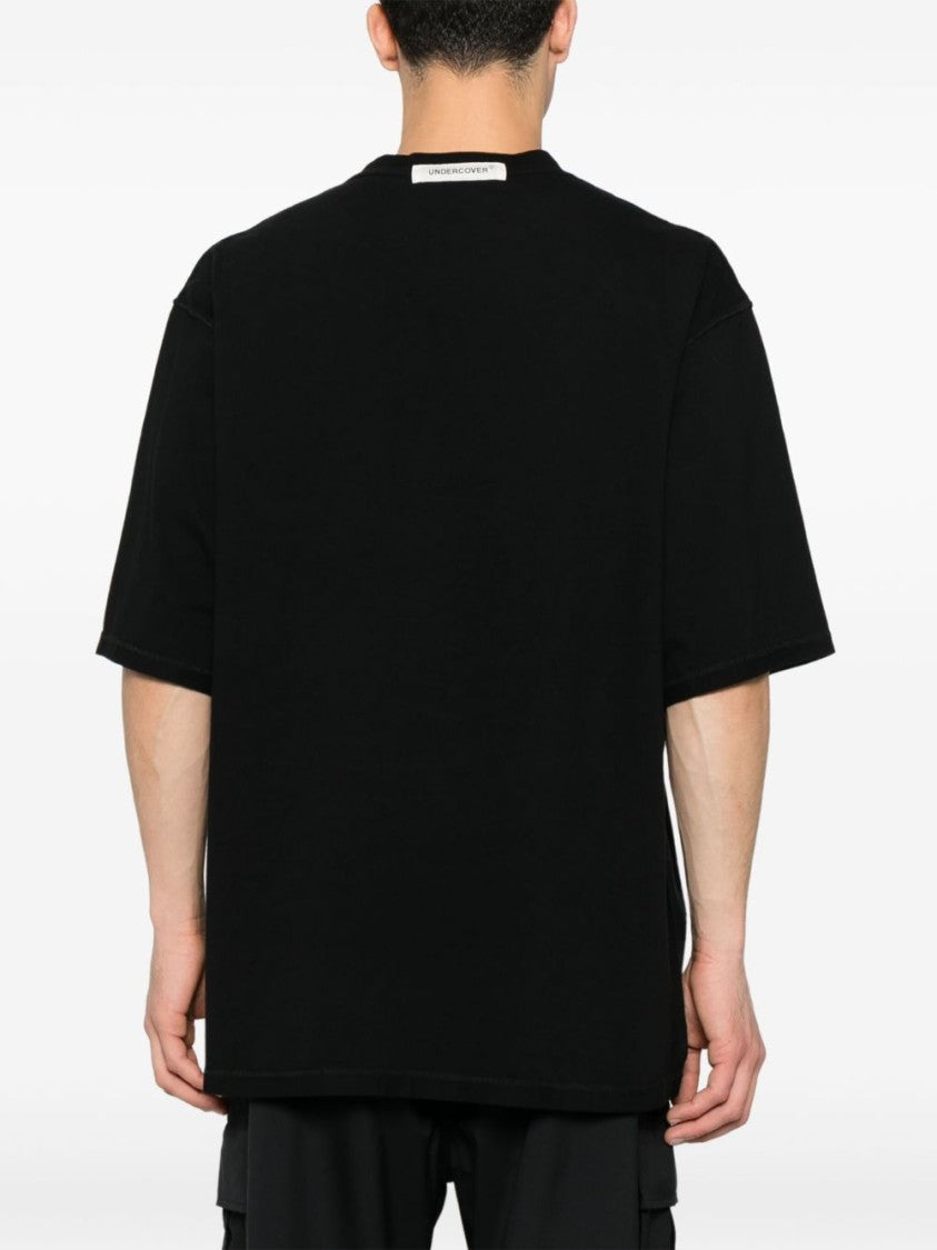 Undercover Graphic Print Black T-Shirt With Exposed-Seam Detailing And Logo Patch